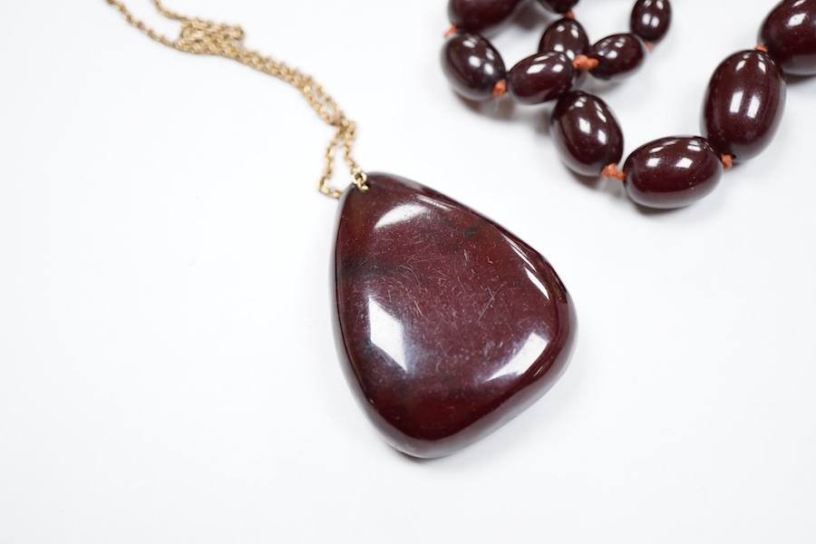 A cherry bakelite 'amber' necklace and pendant, comprising: a necklace composed of cherry-coloured bakelite beads measuring approximately 10 - 26mm, length 90cm, gross weight 72 grams; and a drop-shaped pendant, length 5